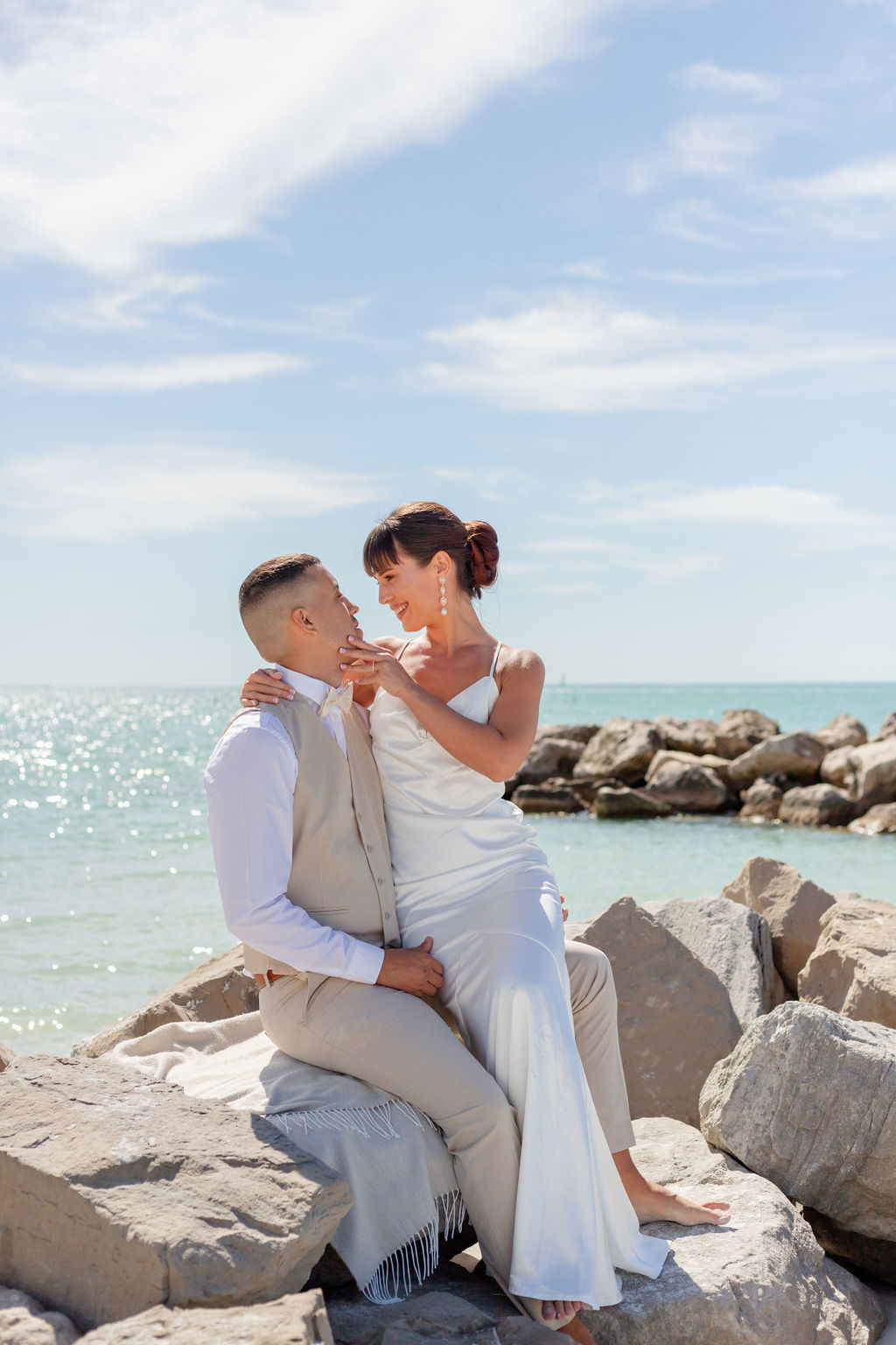 wedding couple sitting at a rocks at a beach