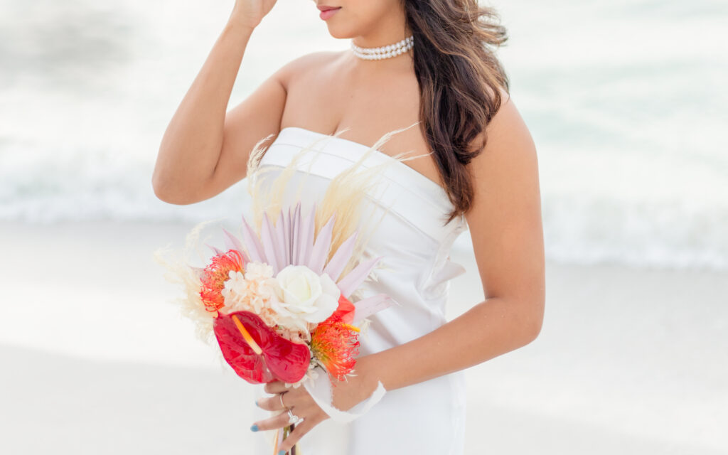 Bride with boho flower bucket at beach wedding