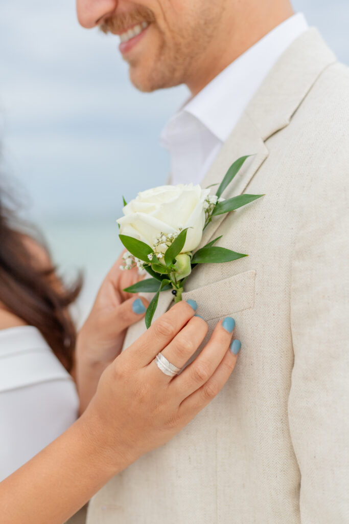 The bride adjusts the groom's flower on the suit