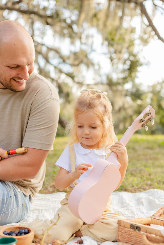 Little girl with a guitar and dad at a park