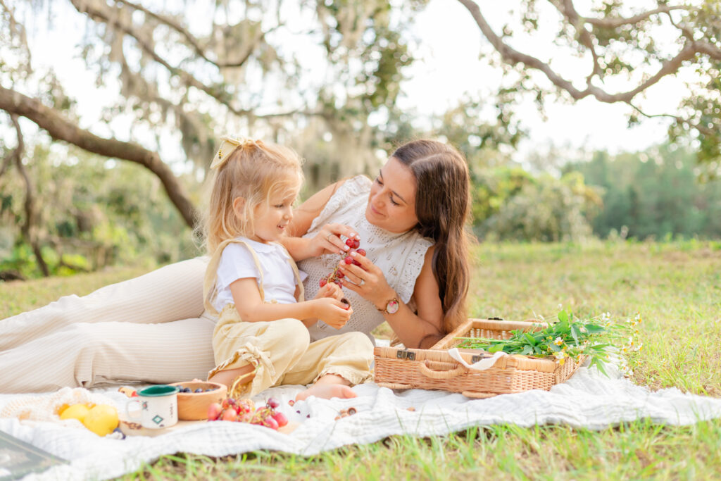 mama and daughter eating grapes at a park picnic